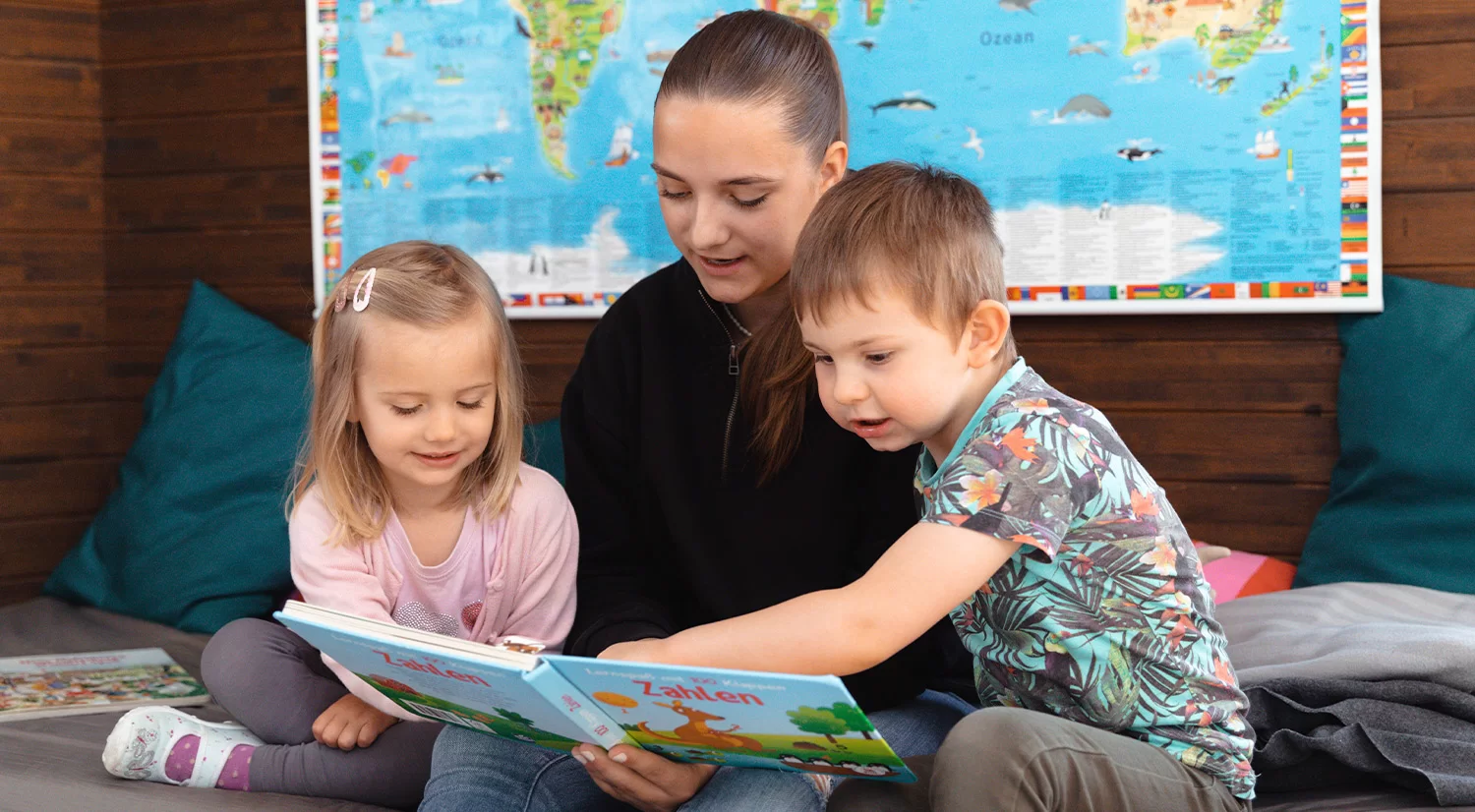 Eine Frau liest mit zwei Kindern ein Buch